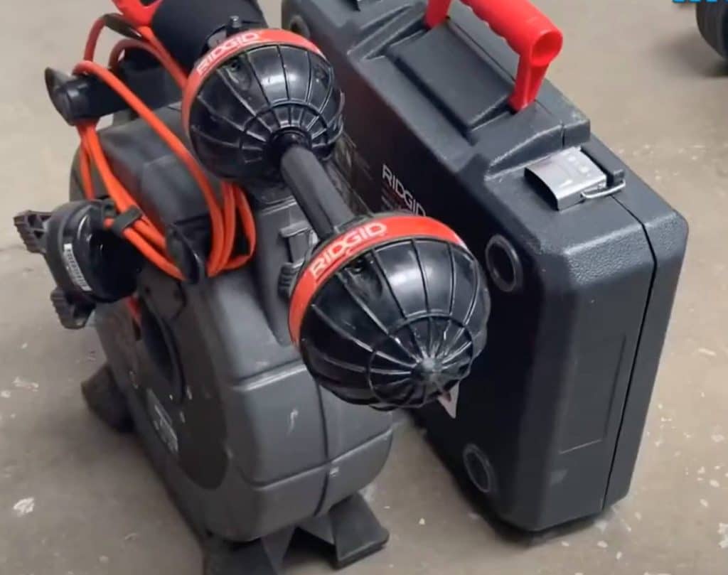 A Ridgid inspection camera system with cables and two camera heads is placed on the floor next to a black Ridgid carrying case with a red handle. | High 5 Plumbing, Heating & Cooling