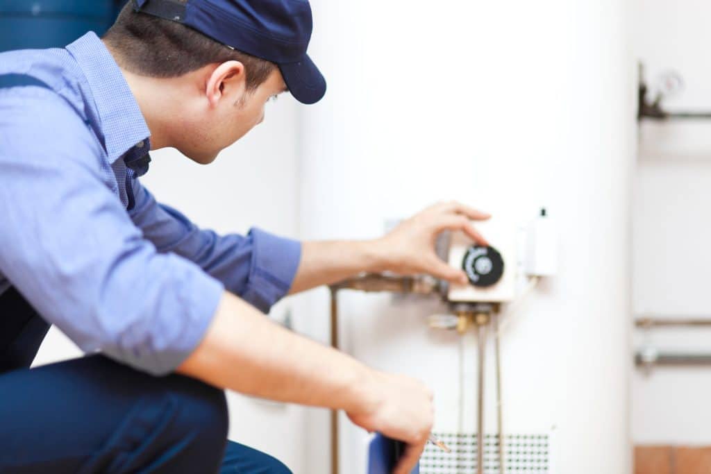 A man performing water heater maintenance, ensuring the system runs efficiently and extends the water heater lifespan. | High 5 Plumbing, Heating & Cooling