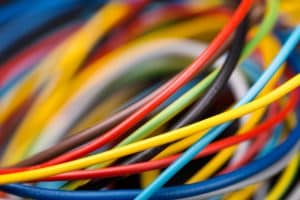 Close-up view of a tangled bundle of colorful electrical wires, including red, yellow, blue, black, and white, demonstrating various thicknesses and textures useful for wire identification and understanding electrical wire color codes. | High 5 Plumbing, Heating & Cooling