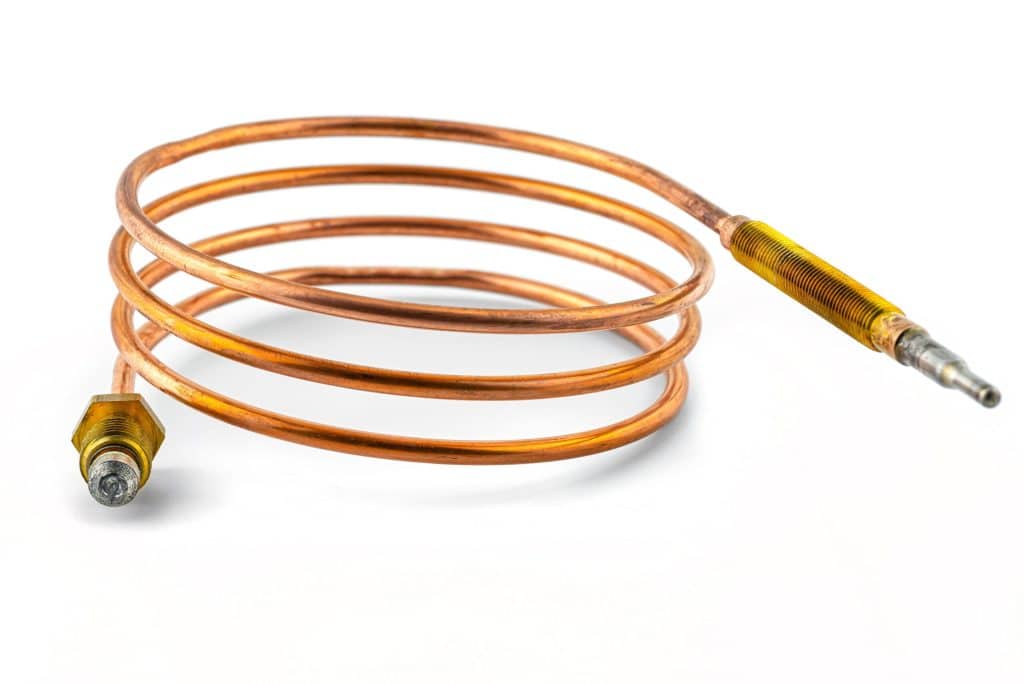 A coiled copper thermocouple, often used in water heaters to detect thermocouple signs or a bad thermocouple, with threaded metallic connectors at both ends, displayed on a white background. | High 5 Plumbing, Heating & Cooling
